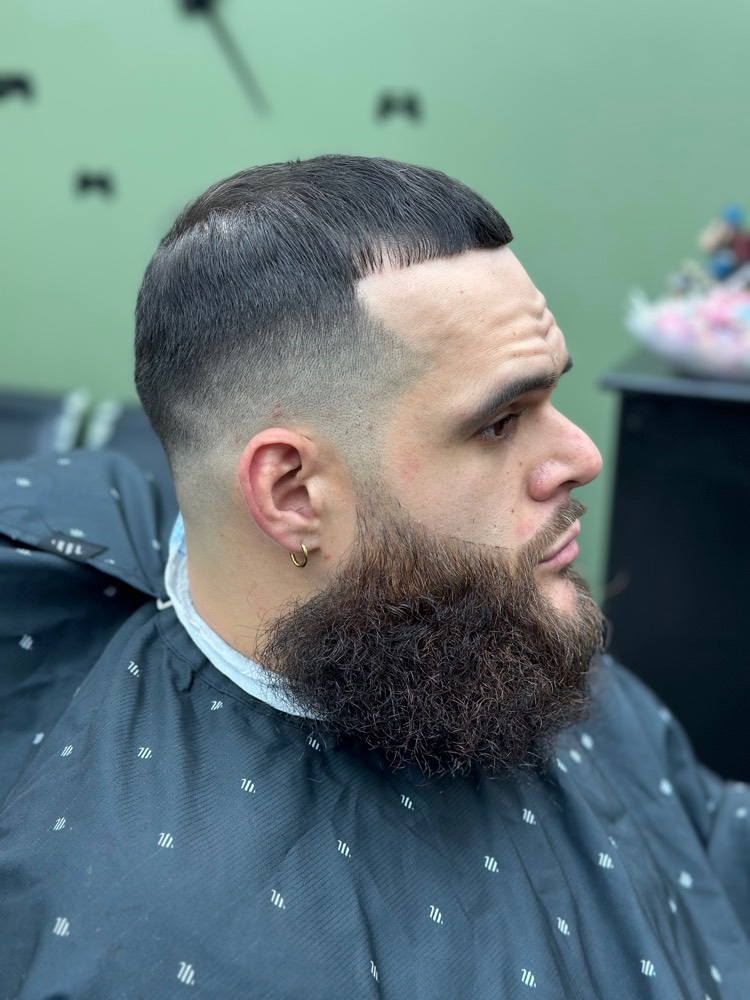 Low taper fade blended into a full sculpted beard