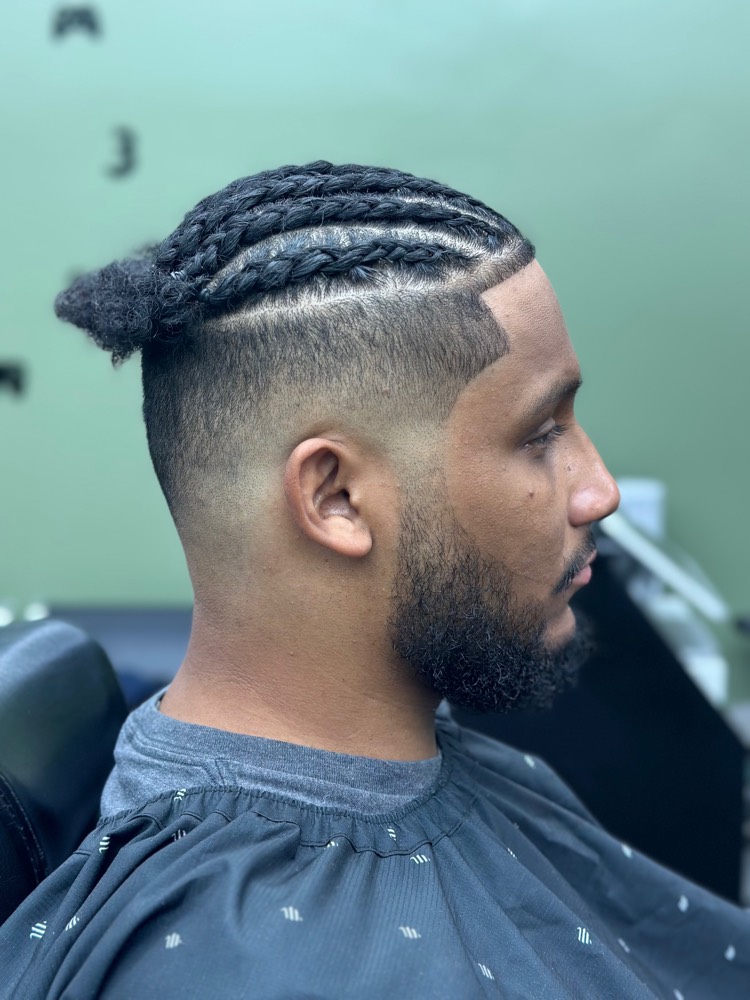 Braided top bun over a high skin fade connected to the beard