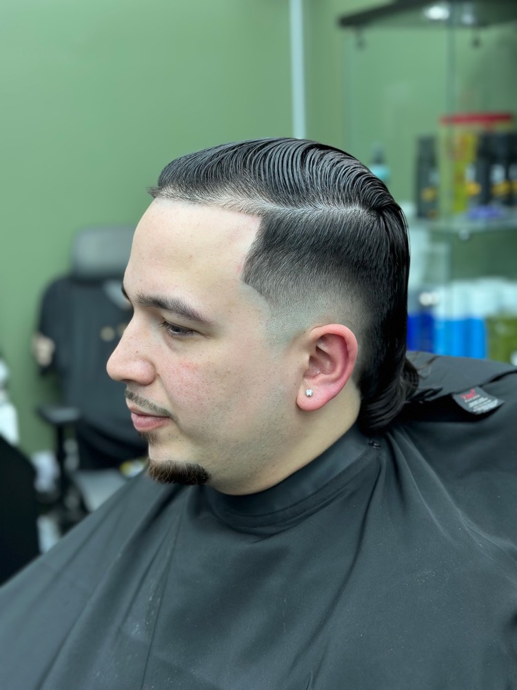 Glossy slicked-back pompadour with hard part and skin fade